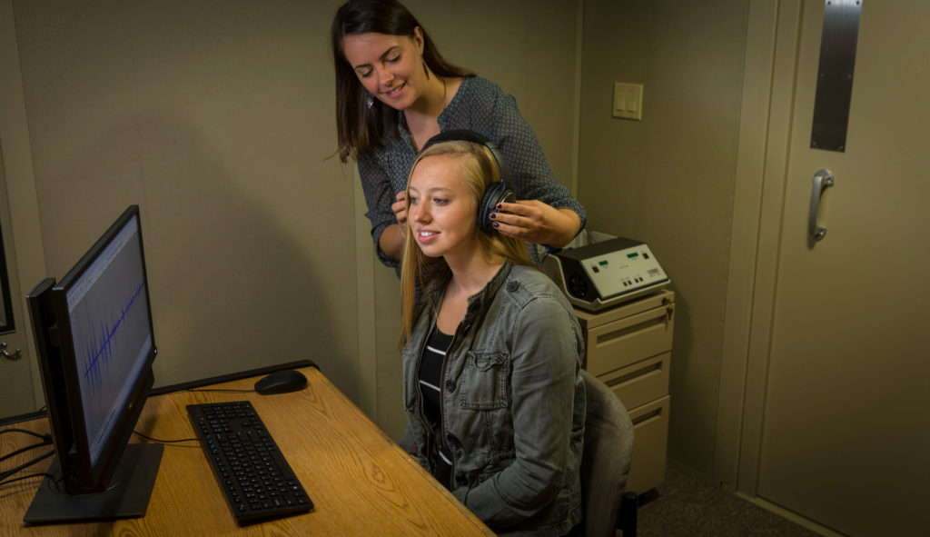 lab member putting headphones on listener